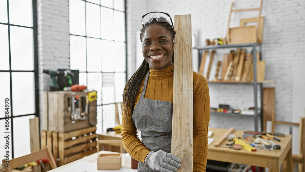 African american woman with braids smiling in a carpentry workshop, holding lumber African american woman with braids smiling in a carpentry workshop, holding lumber