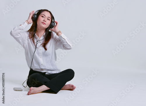 Asian businesswoman relaxing on the floor listening to music on headphones