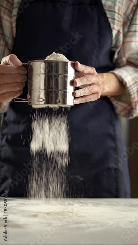 Person is sifting flour in a kitchen using a sifter to prepare homemade baked goods photo