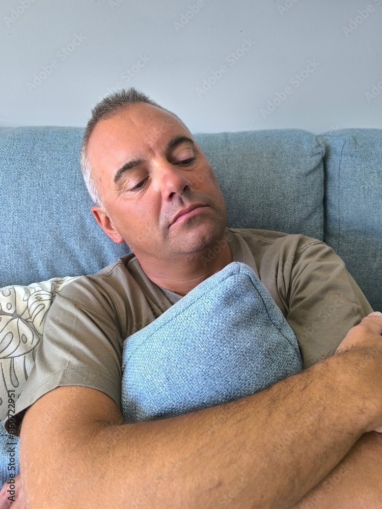 Young adult man sitting on sofa hugging pillow.Man talking to psychologist.Depression.Sadness.Mourning.Divorce.Firing.Panic attack.Man suffering clutching pillow Young adult man sitting on sofa hugging pillow.Man talking to psychologist.Depression.Sadness.Mourning.Divorce.Firing.Panic attack.Man suffering clutching pillow