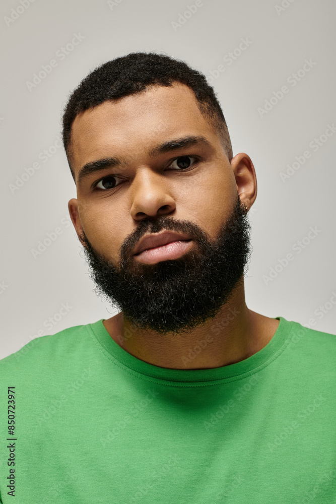 Obraz premium Handsome African American man with a beard confidently posing in a green shirt.