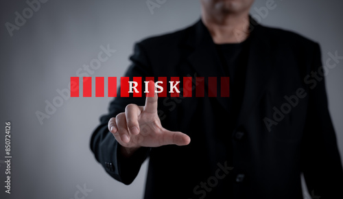 Businessman pointing to a virtual interface with the word "Risk." Represents risk management, technology, and digital assessment in business strategy. 