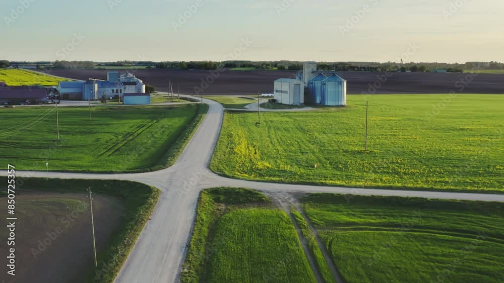 Aerial view with Agricultural landscape. In the foreground is a plowed field, in the background a modern agricultural complex with an animal farm and the steel grain silos for grain drying and storage Aerial view with Agricultural landscape. In the foreground is a plowed field, in the background a modern agricultural complex with an animal farm and the steel grain silos for grain drying and storage