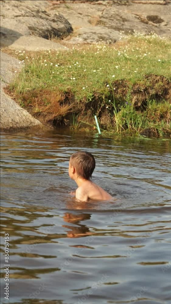 Child playing in a river while bathing and throwing dirt Child playing in a river while bathing and throwing dirt