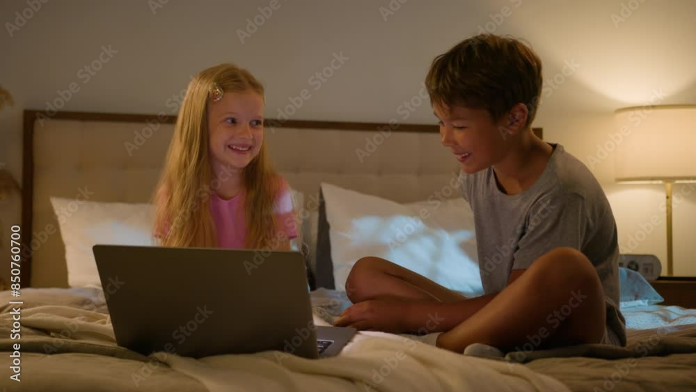 Happy Caucasian relaxed gen z children little kids girl daughter smiling son boy enjoying movie film together night watch cartoon online using computer pc laptop device bed bedroom inside sleepover Happy Caucasian relaxed gen z children little kids girl daughter smiling son boy enjoying movie film together night watch cartoon online using computer pc laptop device bed bedroom inside sleepover