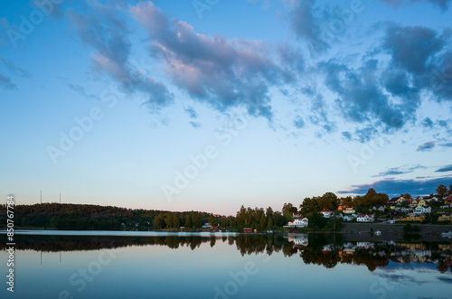 Bengtsfors city by the Lelång lake at Swedish summer night, Nordic town reflecting in calm water at blue hour, Sweden