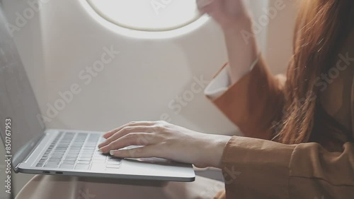 Traveling and technology. Flying at first class. Pretty young businees woman working on laptop computer while sitting in airplane. photo