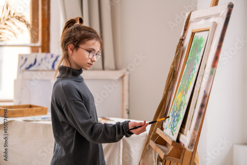 A young girl is painting a picture on a canvas.