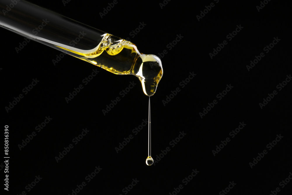 Dripping tincture from pipette on black background, closeup. Space for text