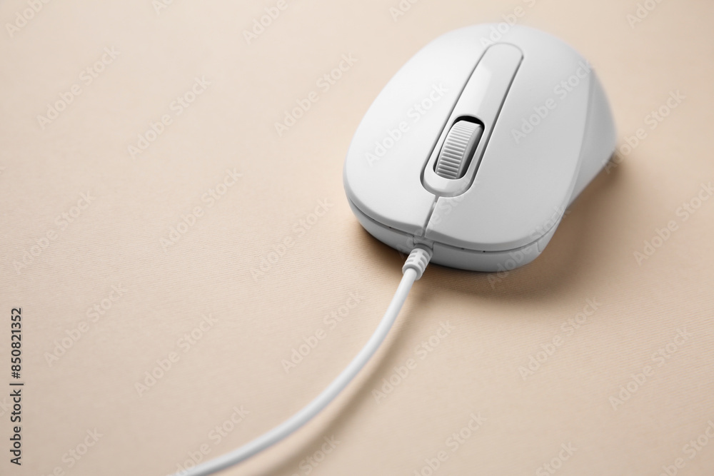 One wired mouse on beige background, closeup One wired mouse on beige background, closeup
