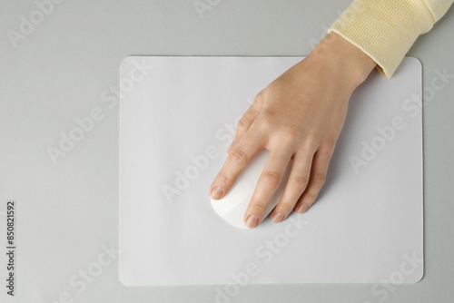 Woman using modern wireless computer mouse on grey background, top view