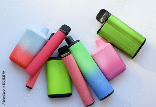 Several multi-colored electronic cigarettes lie on a light table.