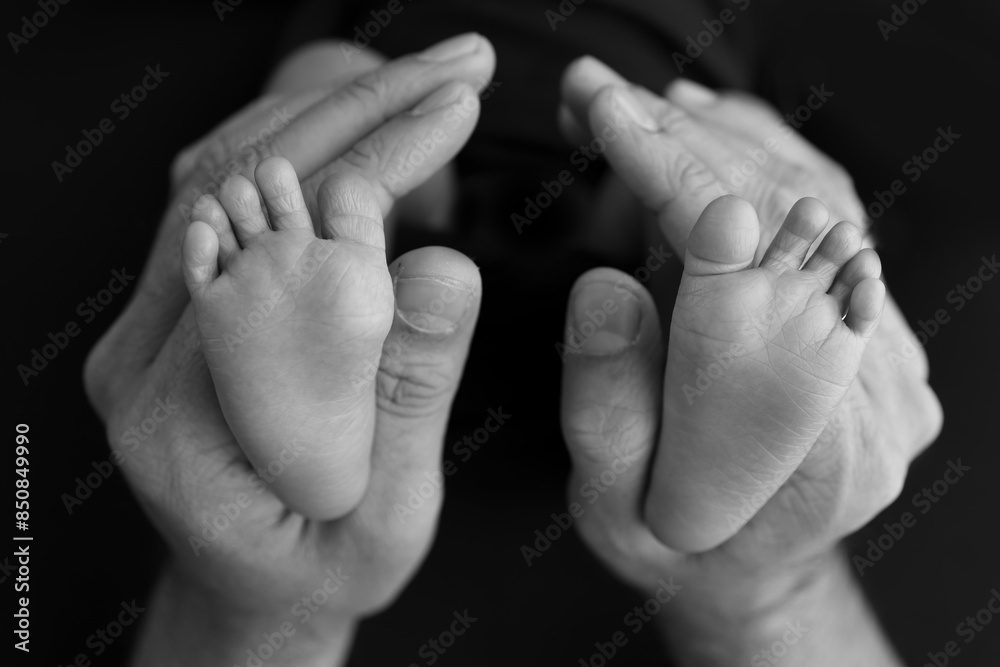 Black and white shade beautiful shape hands of mother, hold tiny newborn baby feet black background Black and white shade beautiful shape hands of mother, hold tiny newborn baby feet black background