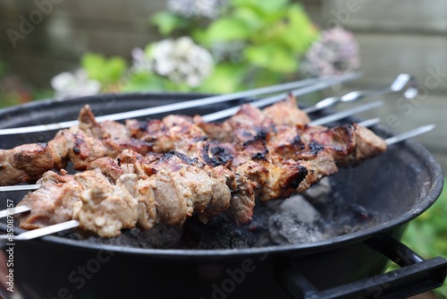 Cooking delicious kebab on metal brazier outdoors, closeup