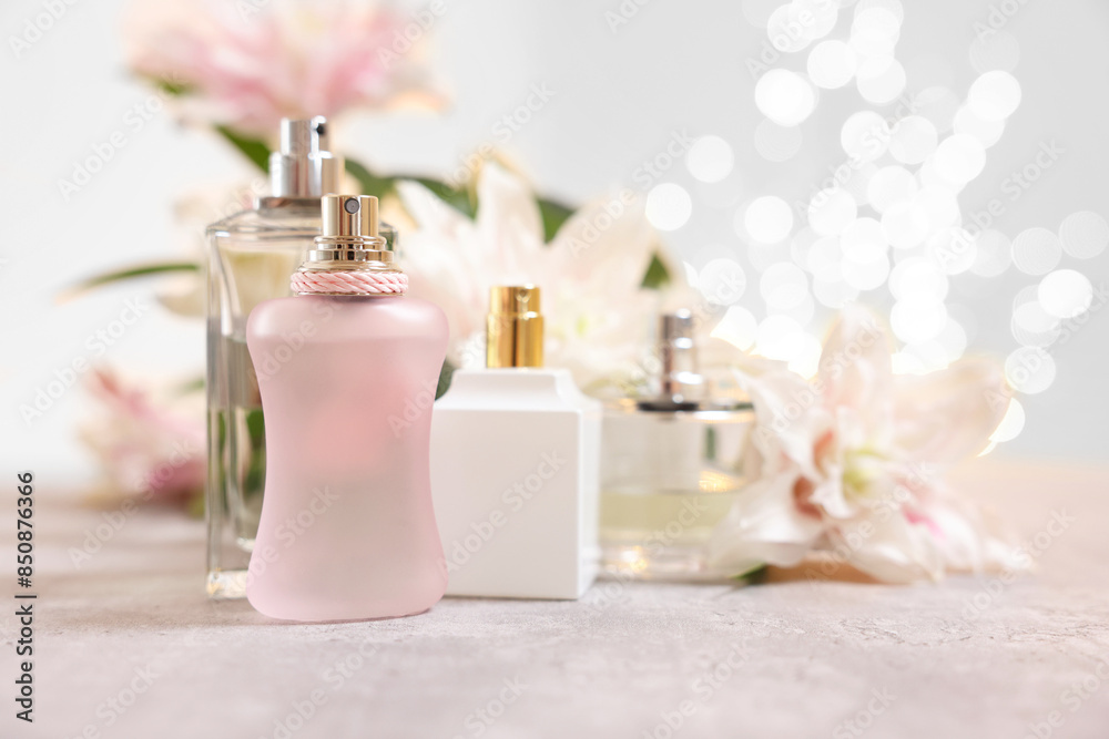 Perfume bottles and bouquet of beautiful lily flowers on table against beige background with blurred lights, closeup Perfume bottles and bouquet of beautiful lily flowers on table against beige background with blurred lights, closeup