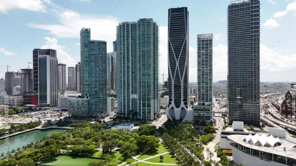 epic sliding drone shot of downtown miami during a sunny day with a park, buildings, and sunny background in south florida