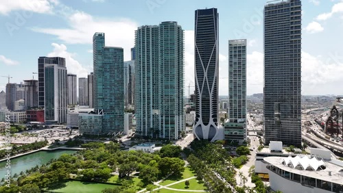 epic sliding drone shot of downtown miami during a sunny day with a park, buildings, and sunny background in south florida