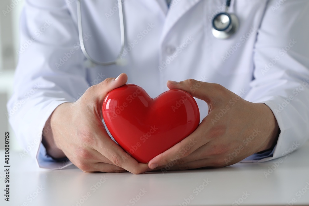 Doctor with red heart at white table, closeup Doctor with red heart at white table, closeup
