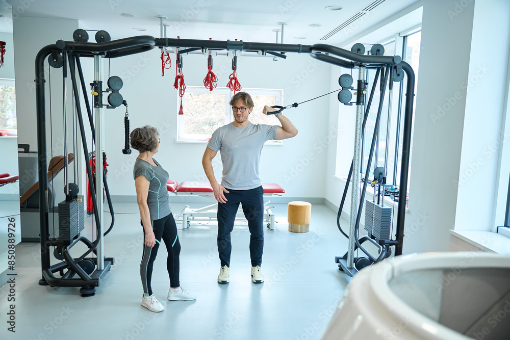 Fototapeta premium Trainer teaches a patient to work on a simulator