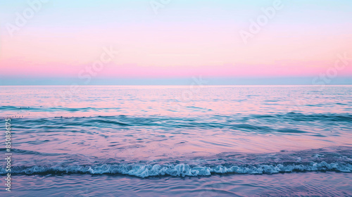 A beautiful beach scene with a pink and purple sky. The water is calm and the sun is setting