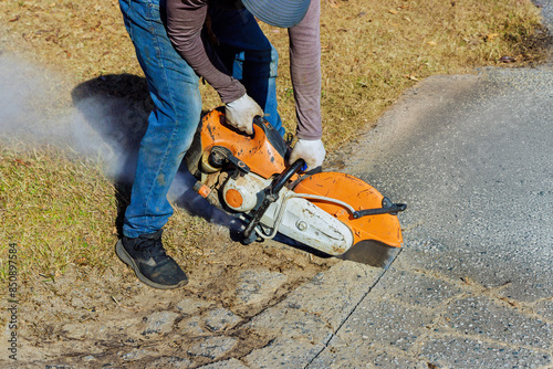 This construction worker uses diamond blade saw machine to cut damaged asphalt pavement