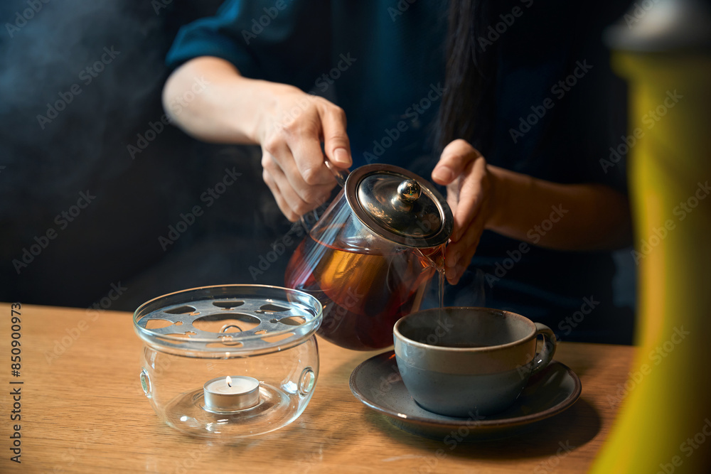 Woman fresh loose leaves tea pouring into the cup