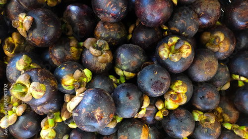 Pile of Fresh Mangosteens at a Market Stall Displaying Dark Purple Fruits with Green Caps in a Vibrant and Detailed Close Up