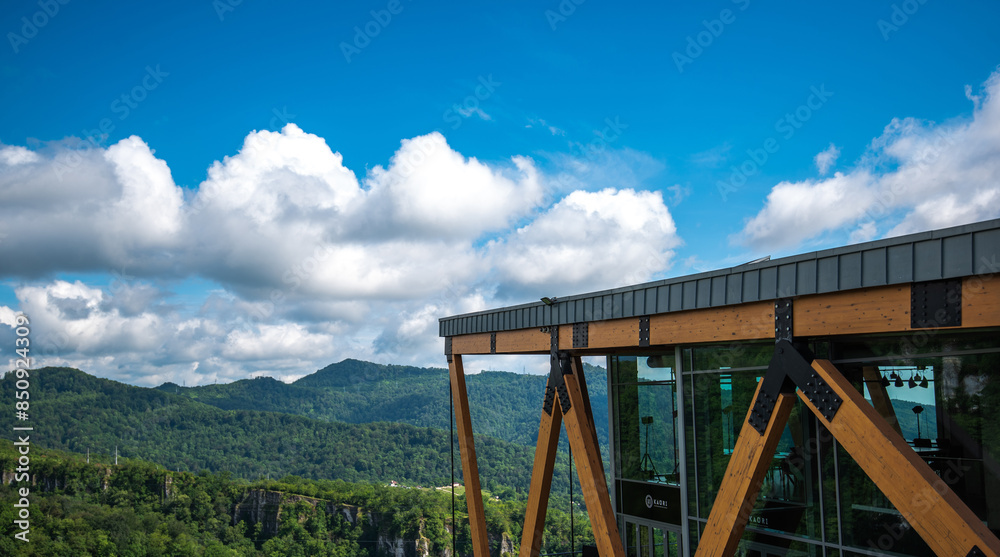 structure of a modern observation platform with wooden beams and glass, offering visitors a panoramic view of a lush mountainous landscape under a vast sky with fluffy white clouds structure of a modern observation platform with wooden beams and glass, offering visitors a panoramic view of a lush mountainous landscape under a vast sky with fluffy white clouds
