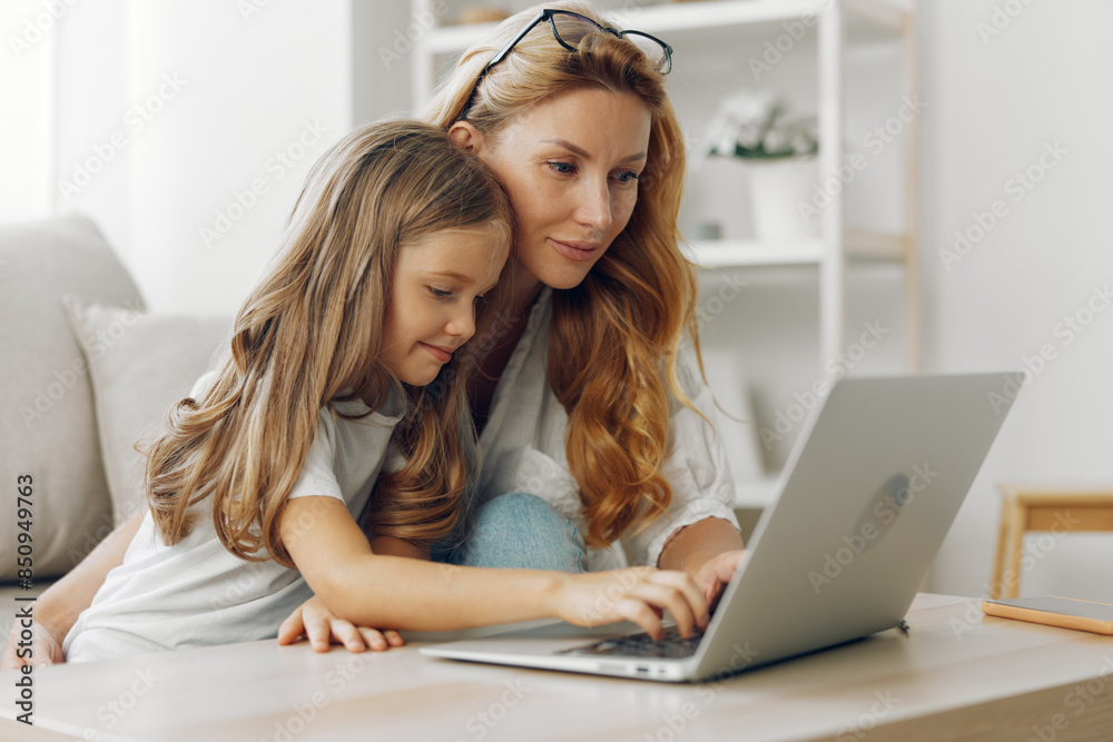 Mother and daughter bonding over a laptop at the kitchen table, sunlit window in the background Mother and daughter bonding over a laptop at the kitchen table, sunlit window in the background