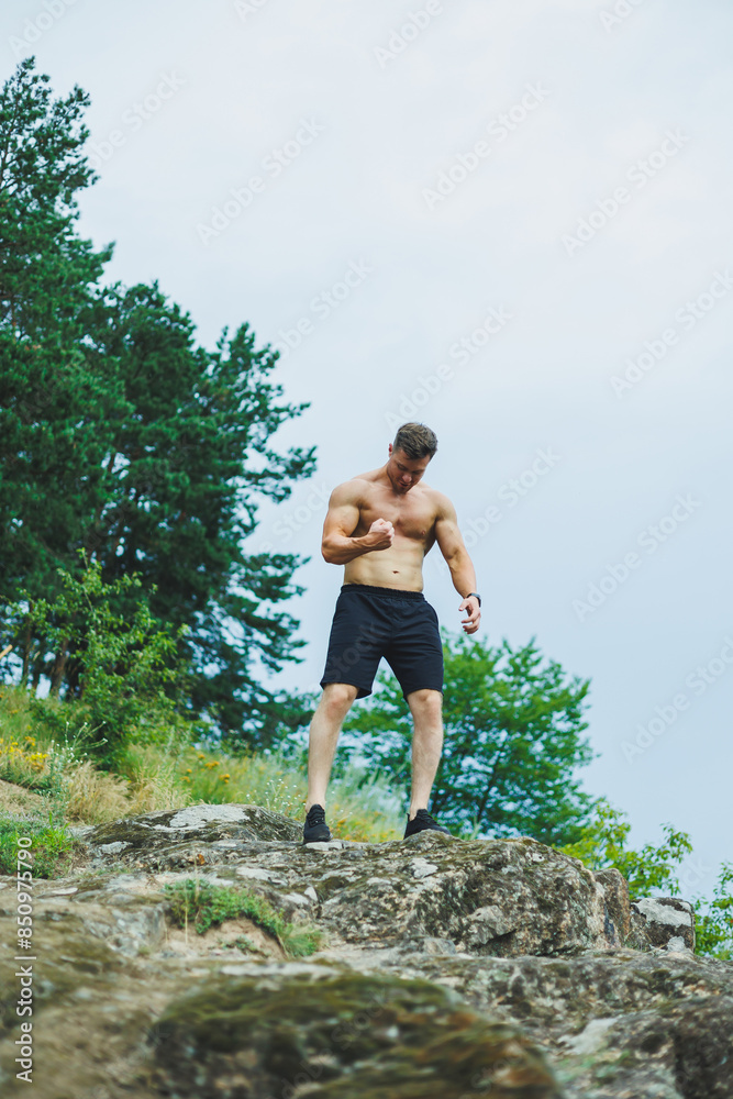Toned shirtless muscular young man in sportswear showing abs outdoors in park. Toned shirtless muscular young man in sportswear showing abs outdoors in park.