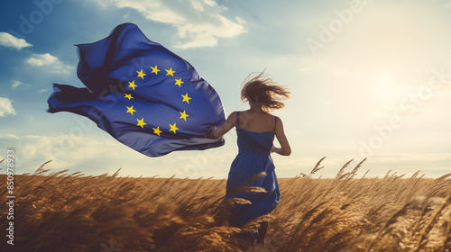 Young woman running on a field with the flag of the EU, freedom and democracy
