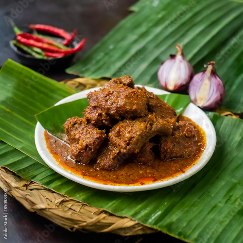 Ready-to-eat beef rendang is served on a large plate covered with banana leaves. Traditional Indonesian food atmosphere. photo