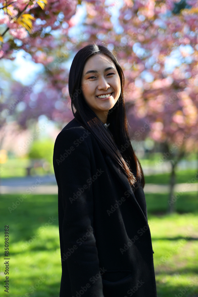 A friendly Japanese woman stands outside, cheerful and confident in a casual, modern setting. A friendly Japanese woman stands outside, cheerful and confident in a casual, modern setting.