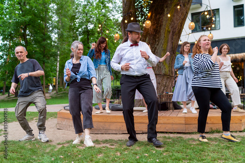 Canvas Print Cheerful dance party outdoors, featuring individuals of different ages enjoying the festive ambiance under illuminated string lights