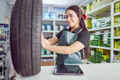 cheerful latina saleswoman holding and checking new tire at the counter in a small auto parts supply store 