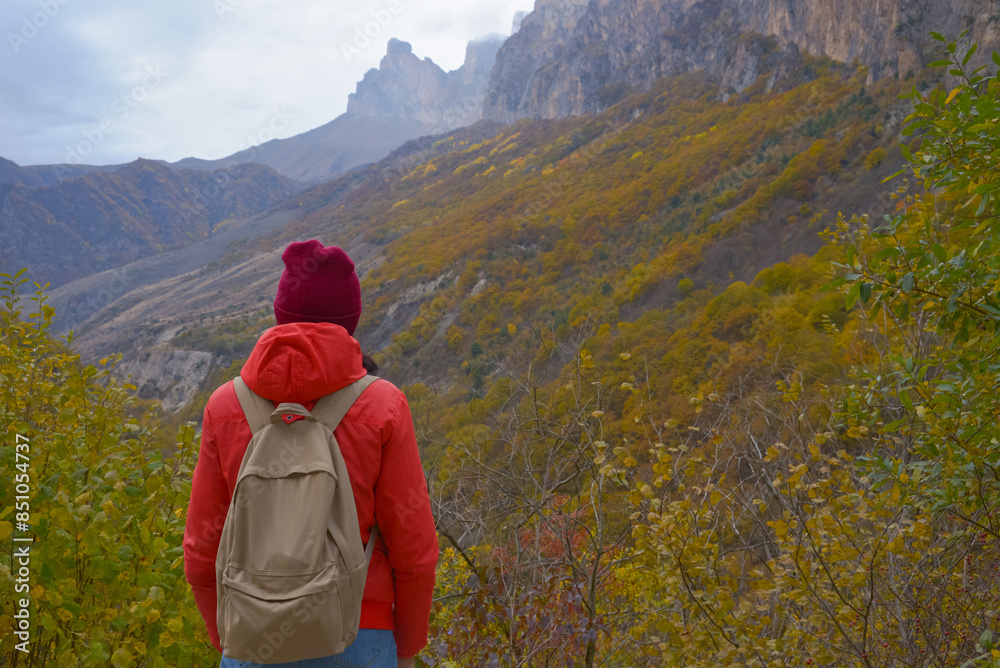Brunette woman with a backpack on her back outdoors exploring the Caucasus Mountains in Russia, traveling, lifestyle, hiking, active autumn holidays, hiking