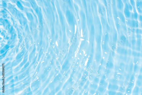 Blue water with ripples on the surface. Defocus blurred transparent blue colored clear calm water surface texture with splashes and bubbles. Water waves with shining pattern texture background.