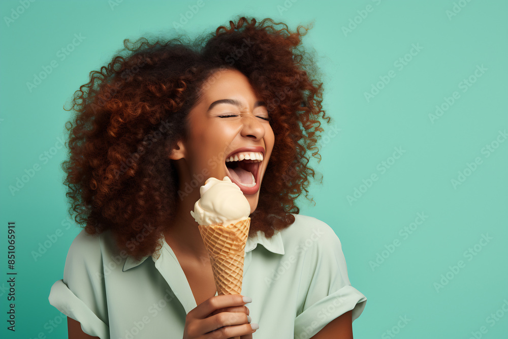 Happy woman eating ice cream cone against a teal background Happy woman eating ice cream cone against a teal background