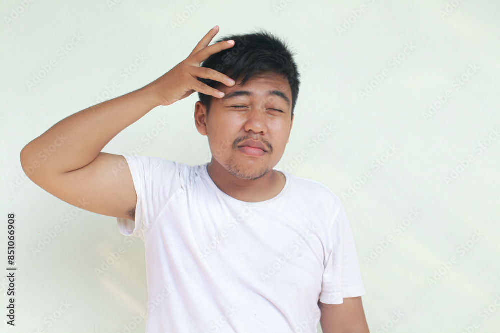 A portrait of an Asian man wearing a white shirt isolated by gray background looks depressed. A portrait of an Asian man wearing a white shirt isolated by gray background looks depressed.