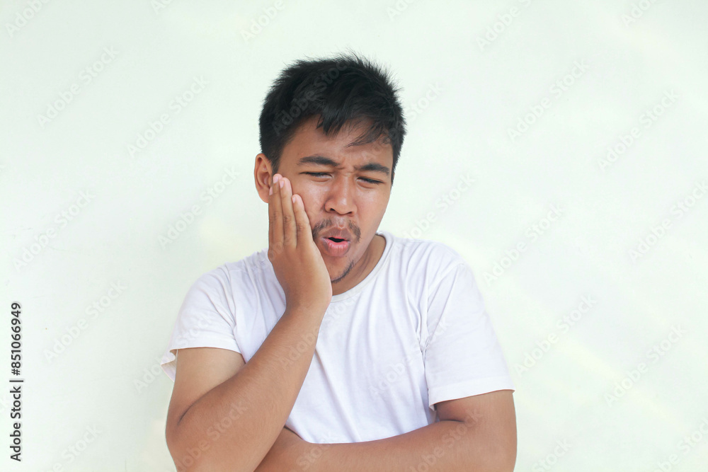 Toothache young Asian man with hurt emotion wear white shirt. Isolated in gray background. Toothache young Asian man with hurt emotion wear white shirt. Isolated in gray background.