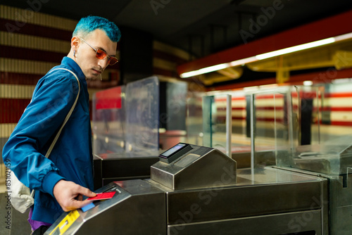 Man with blue hair entering subway station turnstile