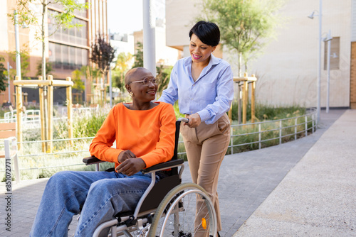 Professional woman assists colleague in wheelchair outdoors