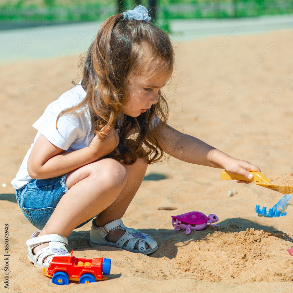 ?ute little girl on playground in sandpit. Child playing with sand molds and making mud pies. Outdoor creative activities for kids ?ute little girl on playground in sandpit. Child playing with sand molds and making mud pies. Outdoor creative activities for kids