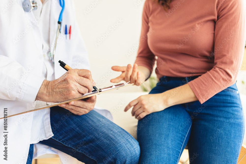 Senior doctor making notes while explaining medical treatment to female patient at medical consultation hospital room. Health care lifestyle concept. Senior doctor making notes while explaining medical treatment to female patient at medical consultation hospital room. Health care lifestyle concept.