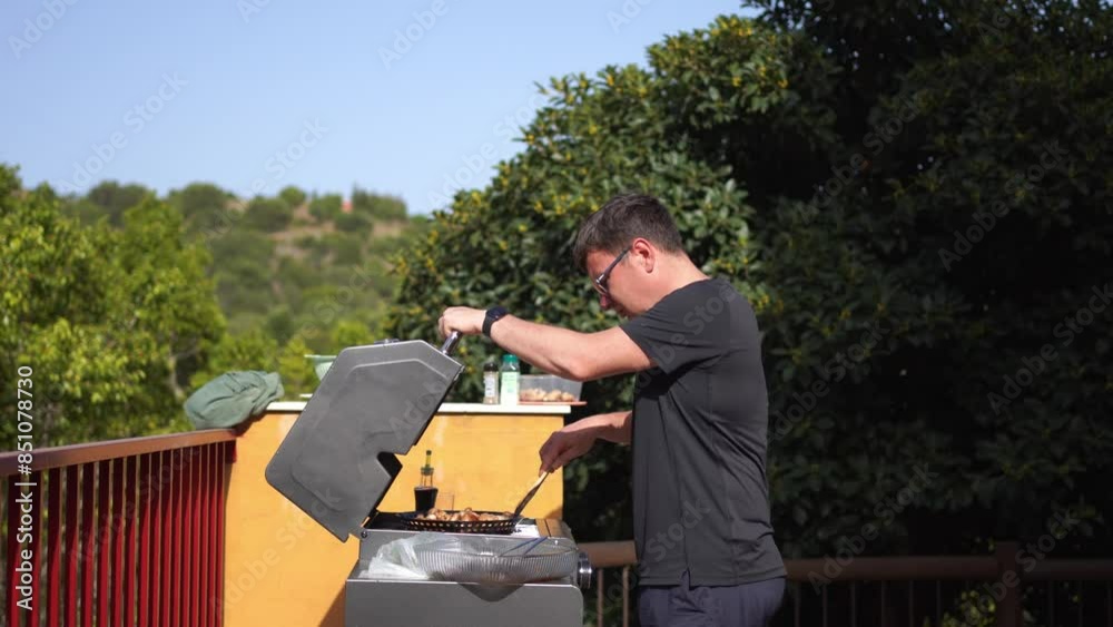 A man grilling food on a gas grill on an outdoor terrace with a scenic view A man grilling food on a gas grill on an outdoor terrace with a scenic view