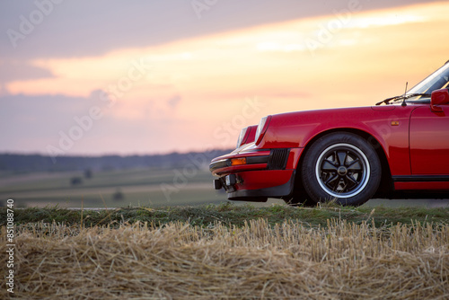 Stimmungsvolle Detailansicht Reifen roter Porsche 911 Sportwagen bei Sonnenuntergang photo