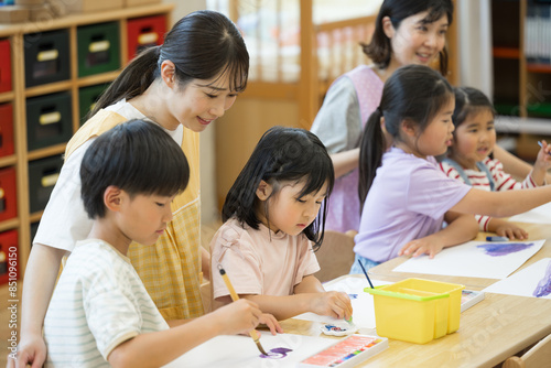 学童や放課後デイサービス等で勉強をする先生と生徒　小学生複数