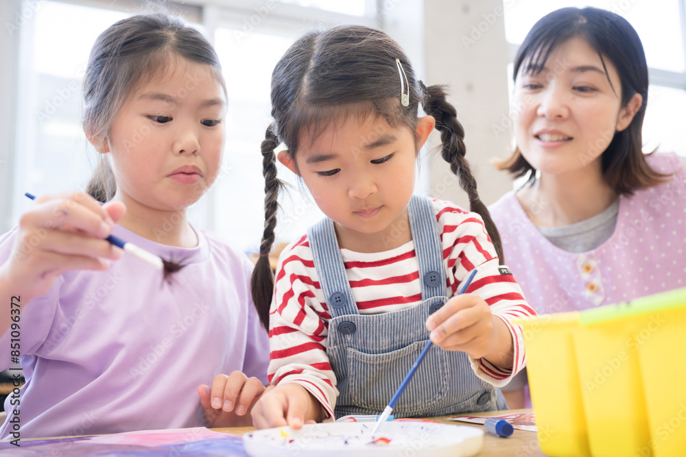 学童や放課後デイサービス等で勉強をする先生と生徒 小学生複数と見守る先生のクローズアップ 学童や放課後デイサービス等で勉強をする先生と生徒 小学生複数と見守る先生のクローズアップ