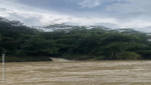 beautiful view of flowing river with bamboo and agit trees in indonesia photo