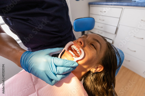 Photography A close-up of a dentist examining a patient's teeth using a mouth retractor in a modern dental clinic